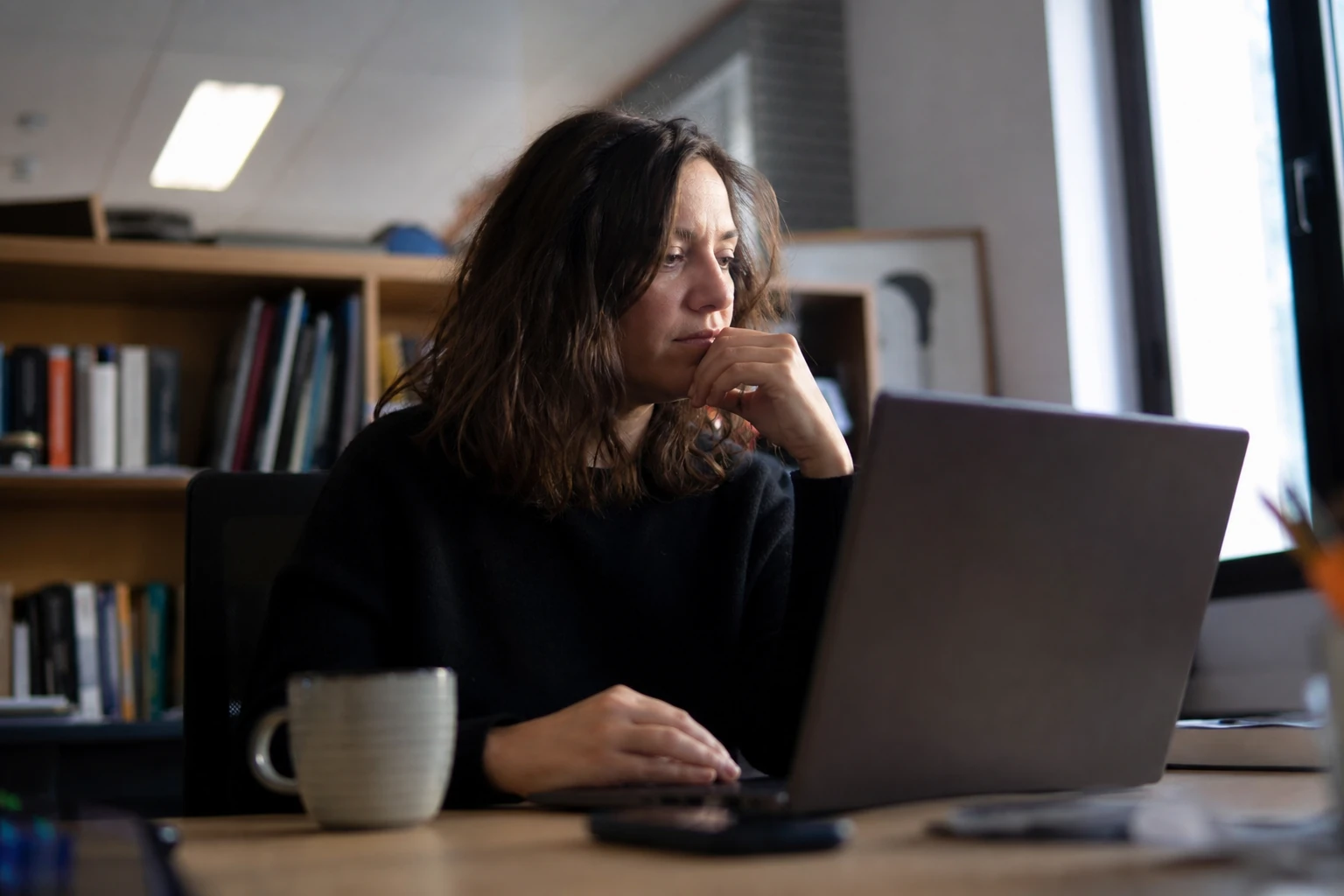 A small-business owner planning her content at a modest desk, laptop screen turned away, soft afternoon light