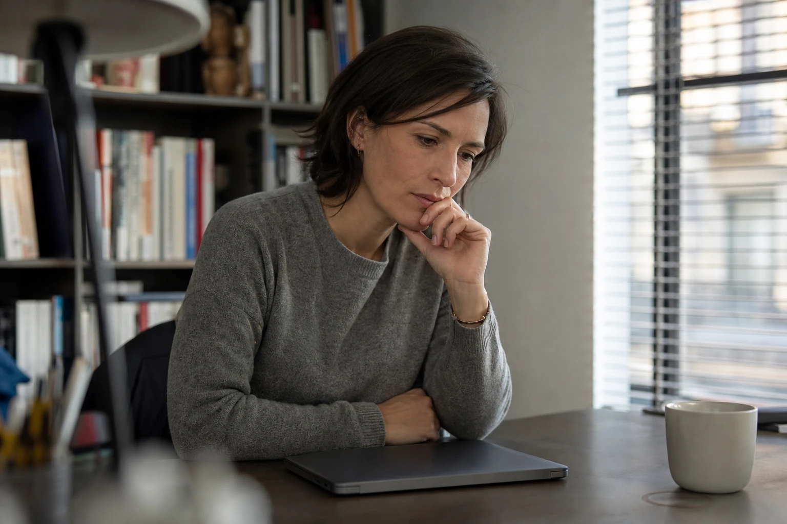 A marketing professional looking at a closed laptop in a small agency office at the end of the day