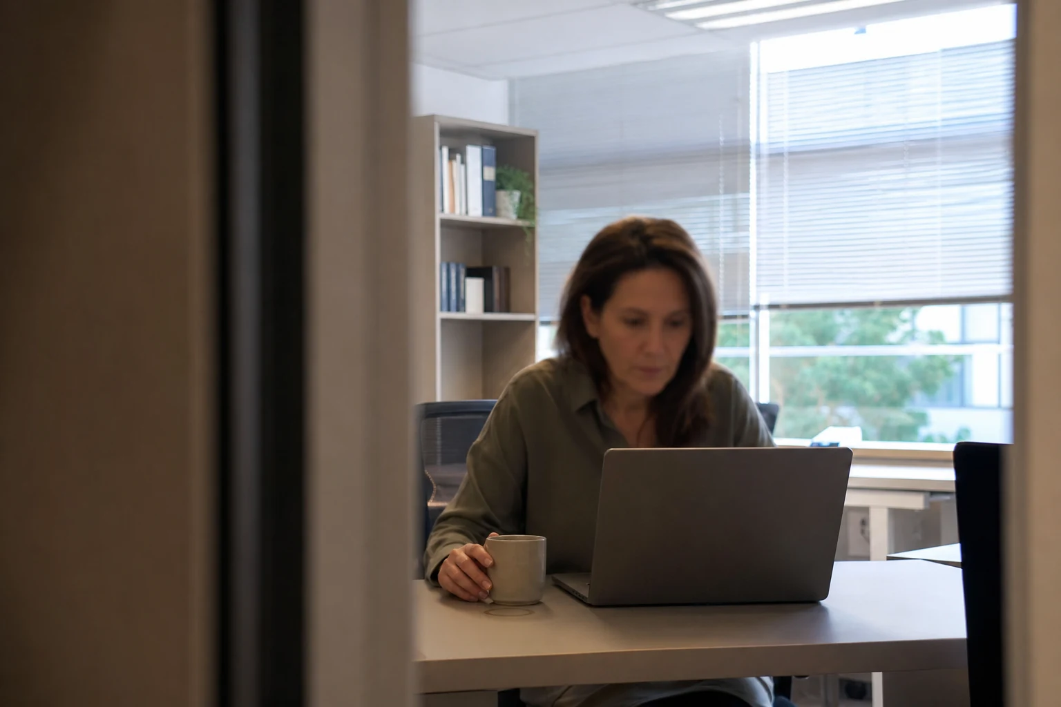 Une personne relit une information sur un ordinateur portable dans un bureau, image du contrôle humain exigé sur les contenus YMYL produits avec l'IA
